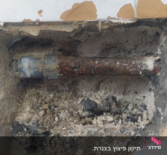 צינור חלוד בקיר עם טיח מתפורר